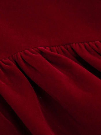 Detail of the gathered seam and draped fabric on a deep red velvet Lillie Bow Mini Dress, showcasing texture.
