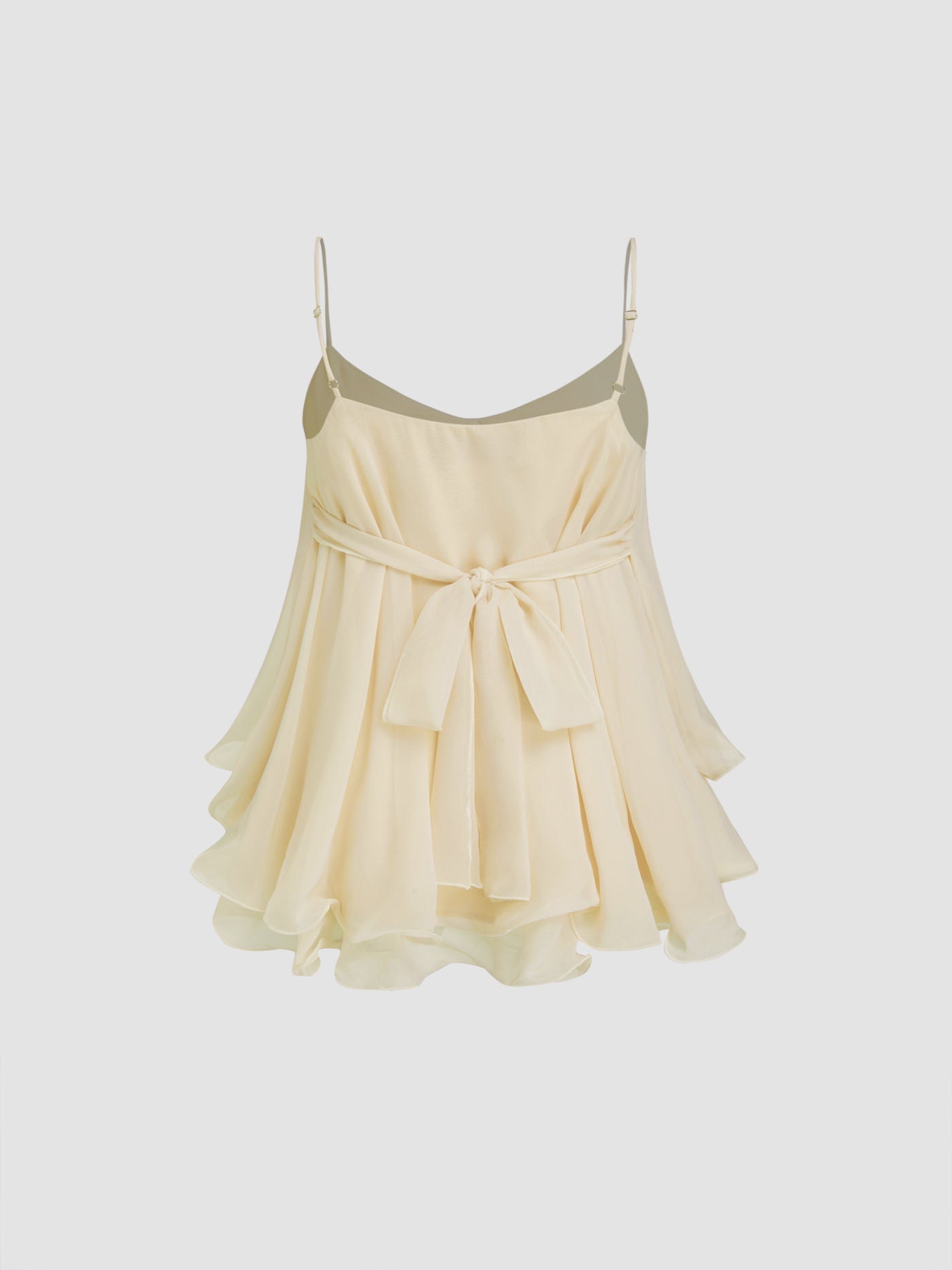 Back view of a cream Lily Ruffle Cami Top, showcasing the delicate tie-back detail and the flowing layered ruffles on a neutral background.