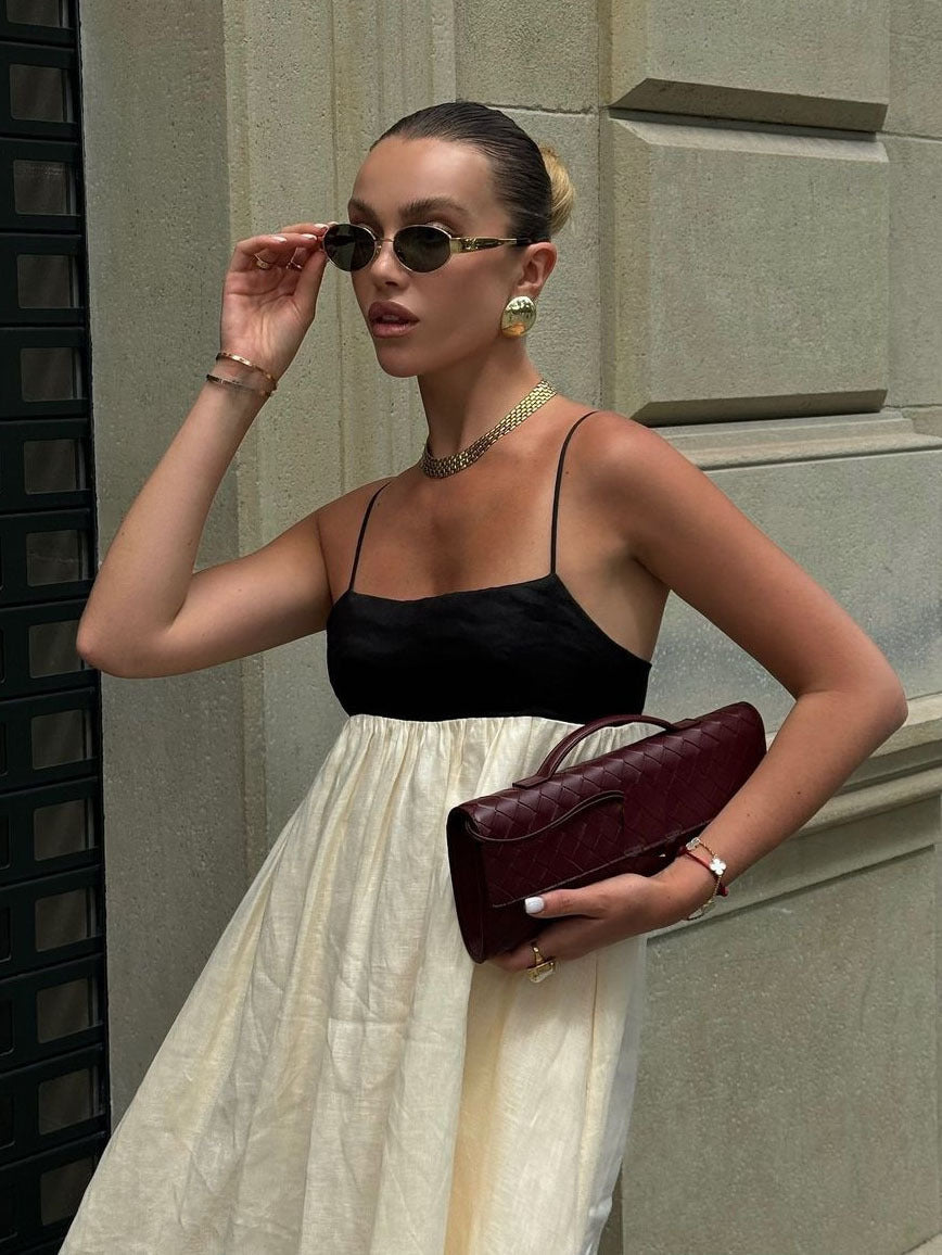 Close-up of a woman in a cream and black color-block maxi dress showing the spaghetti straps and square neckline.
