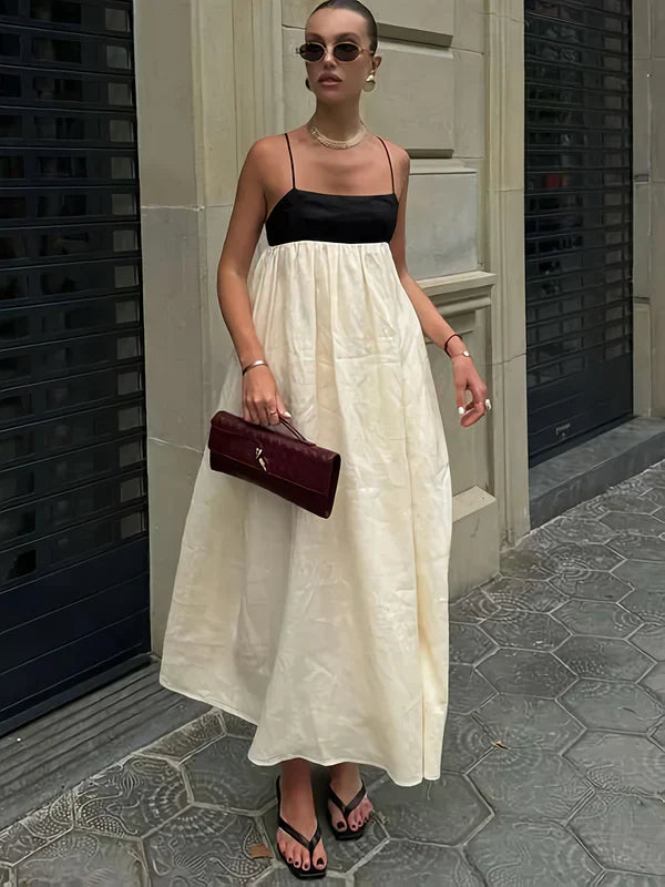 Cream and black color-block maxi dress with spaghetti straps for women, styled with sunglasses and a clutch.