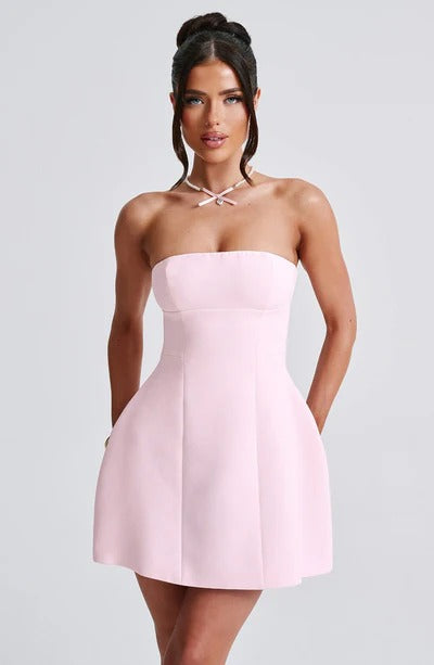 Front view of a woman wearing a light pink strapless Lola Bubble Mini Dress with a pearl necklace, ideal for a spring event.