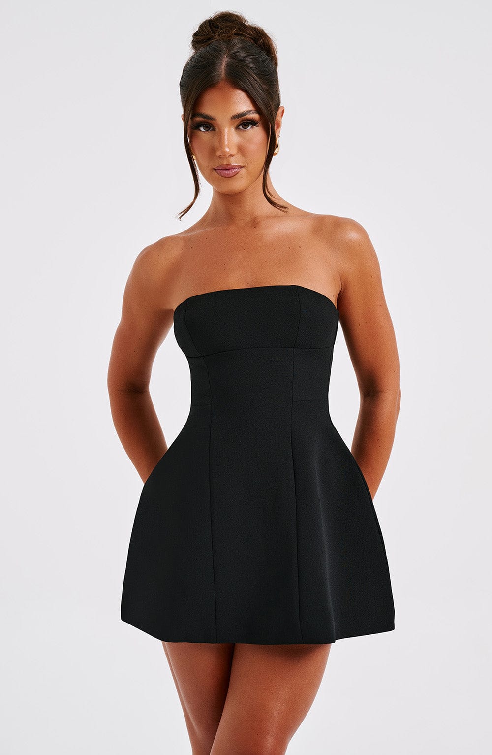 Close-up of a black strapless mini dress, highlighting the structured bodice and subtle seam details.