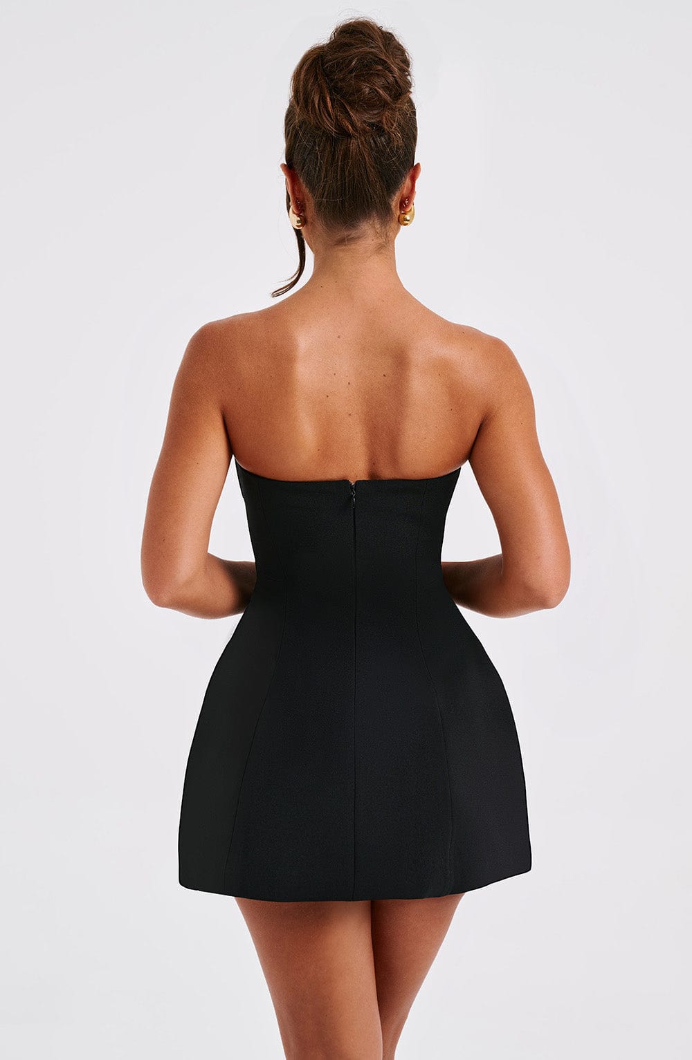 Back view of the black strapless mini dress, showcasing the invisible zipper closure and the bubble skirt's shape.