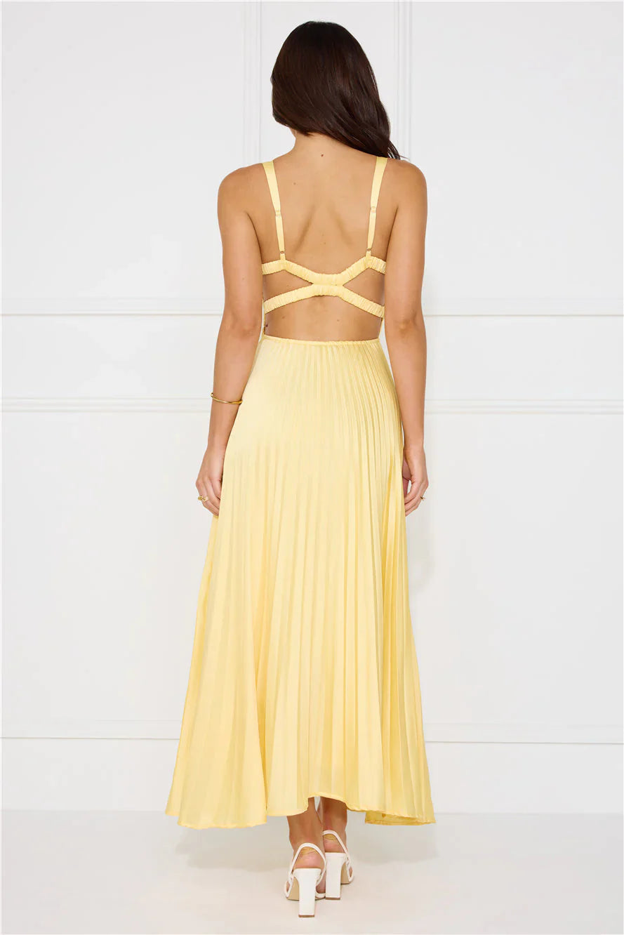 Back view of a woman in a light yellow pleated maxi dress with intricate cut-out strap details for women