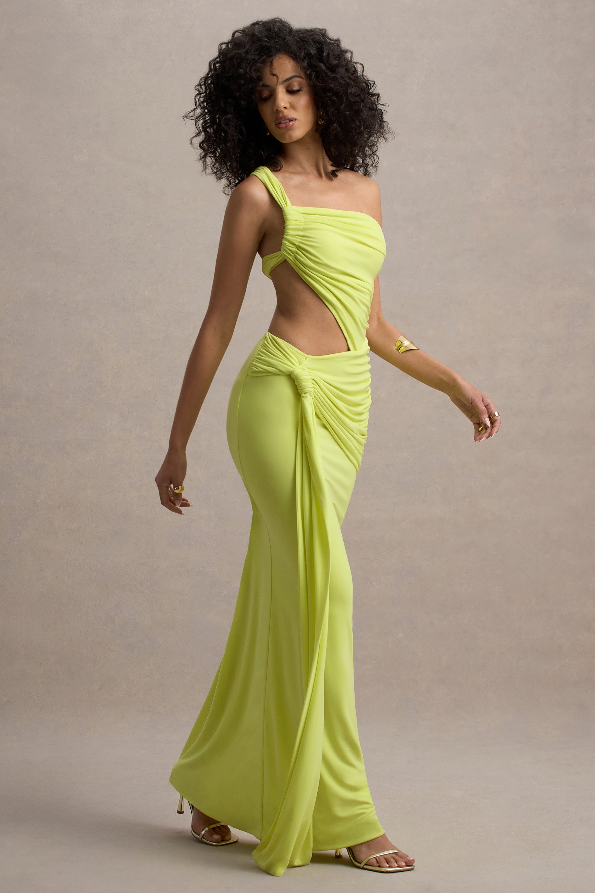 Model walking in a neon yellow Lorelei Cutout Maxi Dress, showcasing the one-shoulder silhouette and flowing skirt with side cutout.