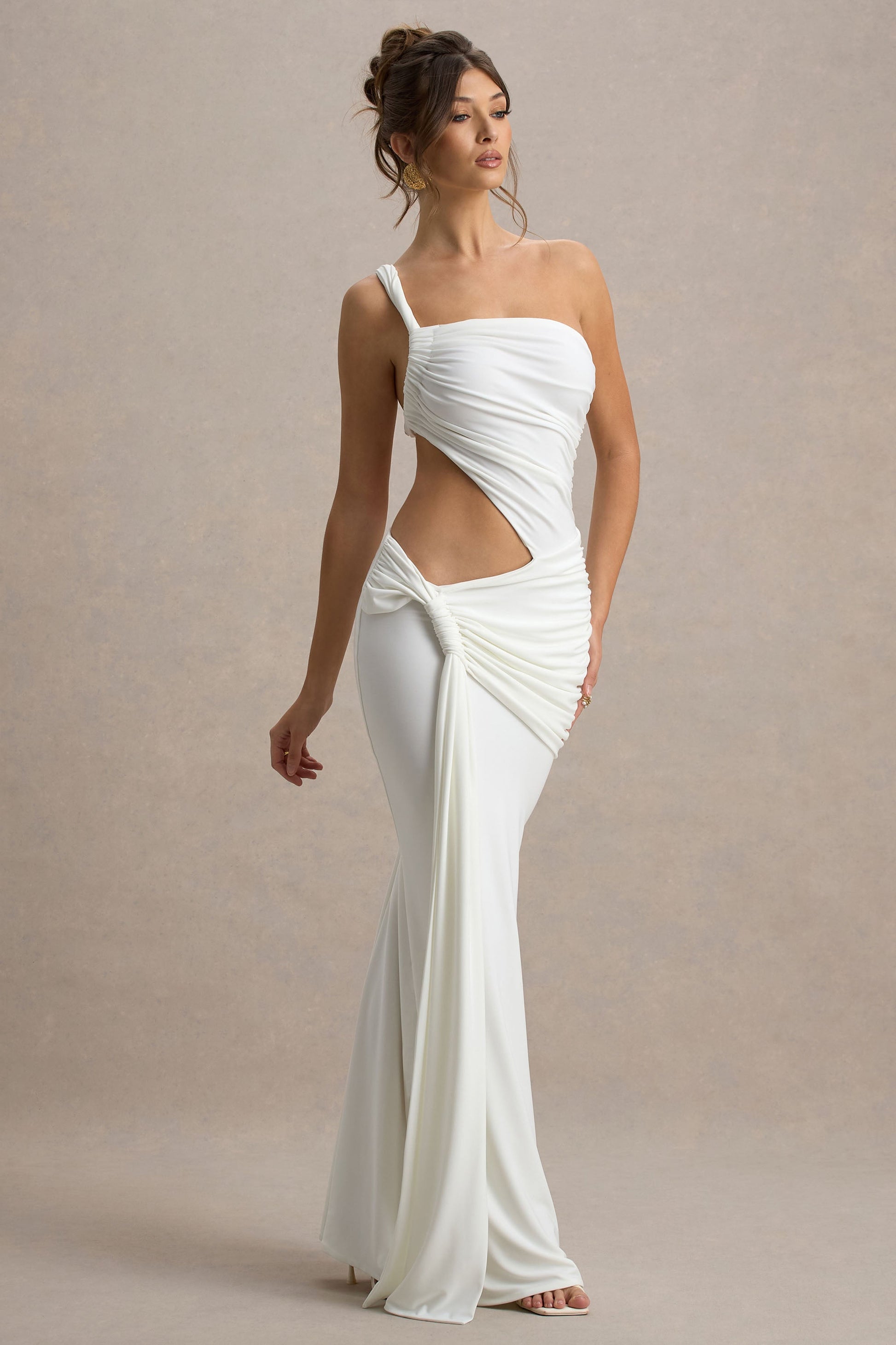 Model walking in the white Lorelei Cutout Maxi Dress, showcasing the form-fitting design and the elegance of the draped fabric.