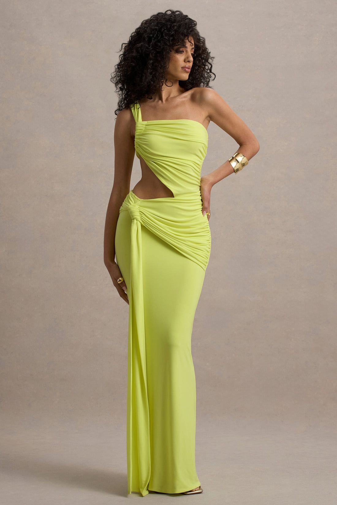 Full-length Lorelei Cutout Maxi Dress in bright neon yellow with one shoulder strap and side cutout, draped knot detail at waist.