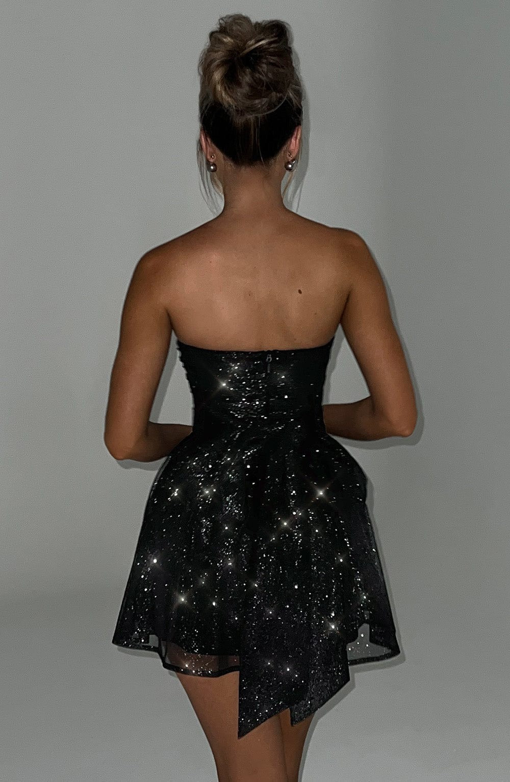 Back view of the black glitter mini dress, showing the strapless design and the subtle sparkle of the fabric.