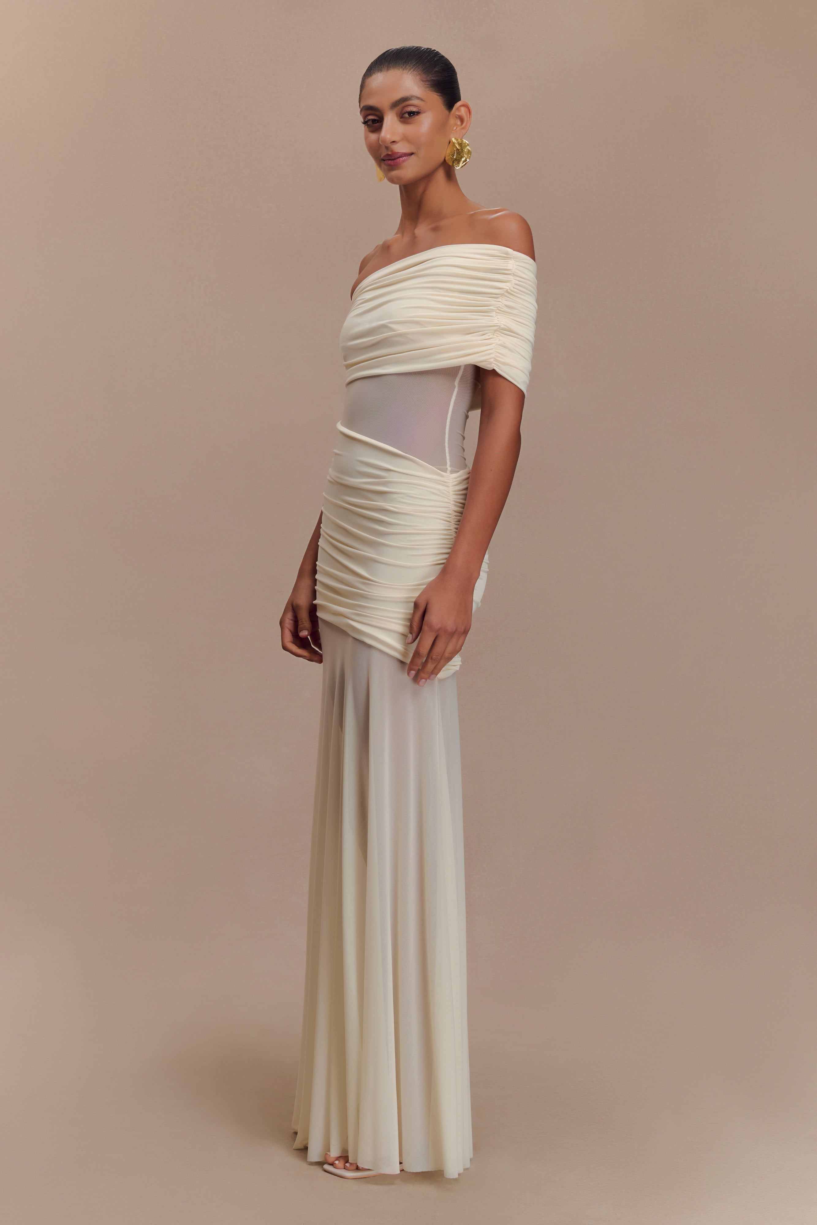 Full-length ivory Luella cutout maxi dress with sheer mesh panels and ruched off-the-shoulder design, front view.