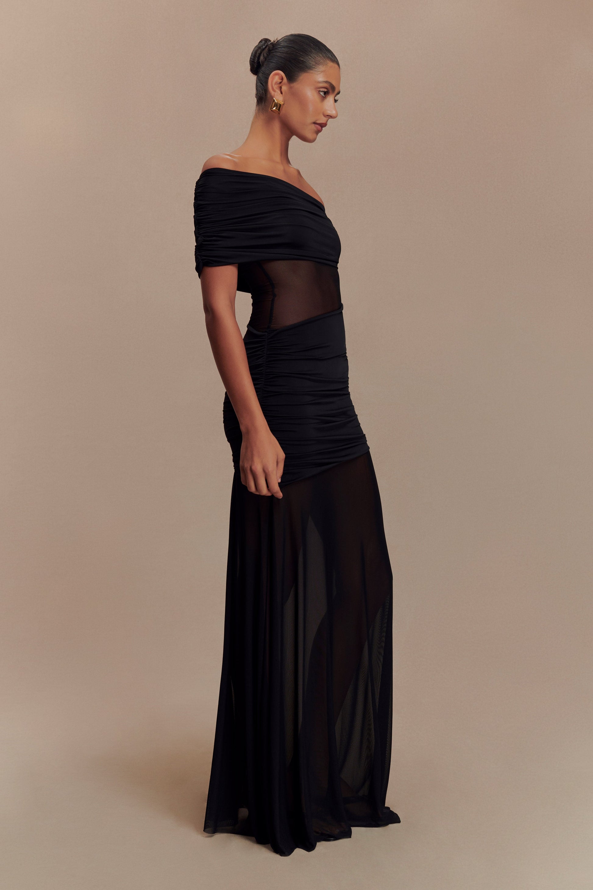 Side profile of the black Luella cutout maxi dress, highlighting the off-the-shoulder neckline and sheer skirt.
