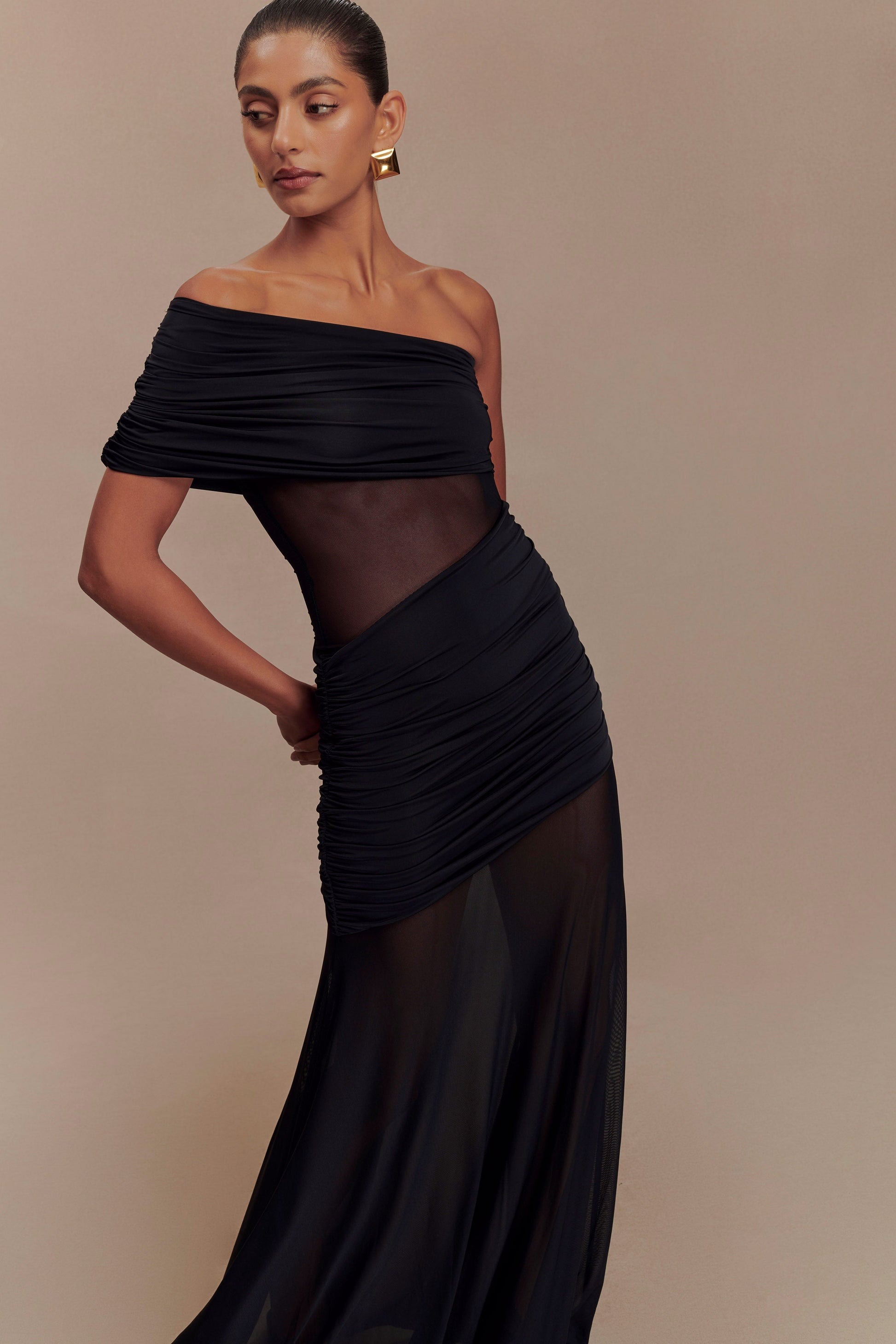 Three-quarter view of the black Luella cutout maxi dress, showcasing the off-the-shoulder design and flowing skirt.