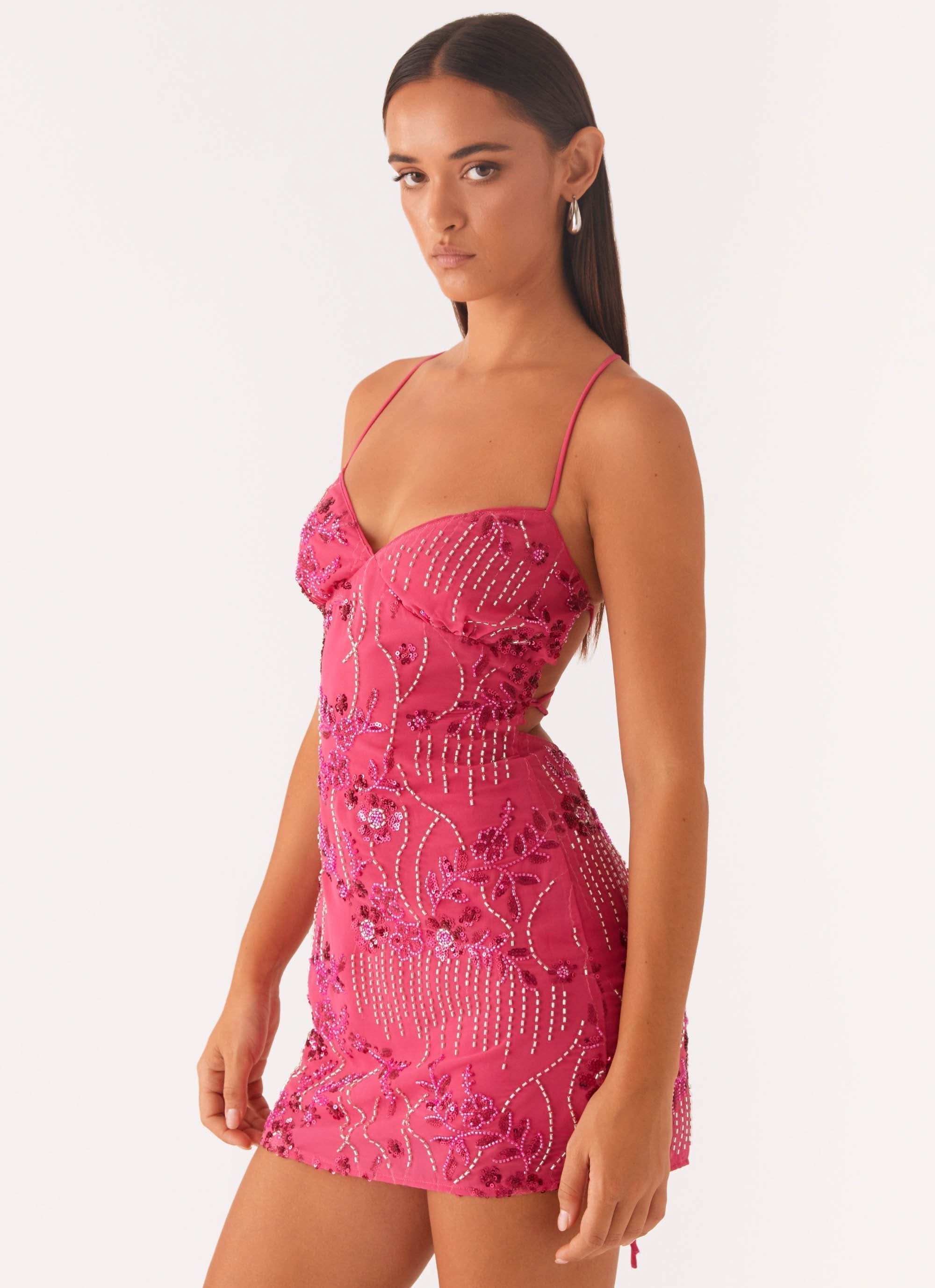 Diagonal view of a pink sequin mini dress, highlighting the sweetheart neckline and side cut-outs.
