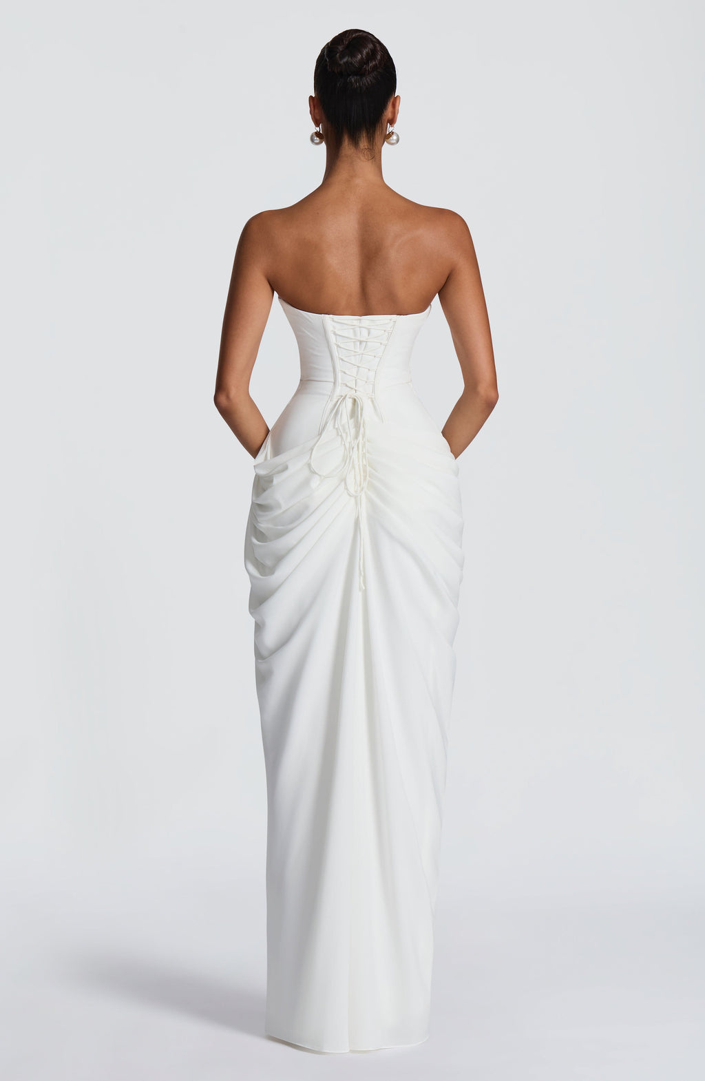 Back view of white ruched maxi dress with lace-up corset back and gathered draped skirt