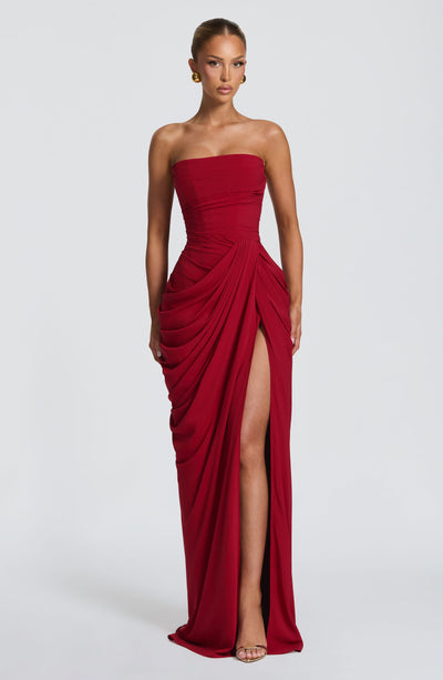 Strapless red ruched maxi dress with draped skirt and high slit, full length front view