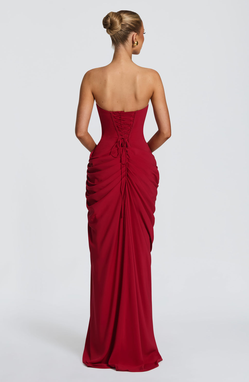 Back view of red ruched maxi dress with lace-up corset back and gathered skirt drape