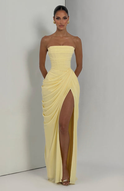 Pale yellow strapless ruched maxi dress with side draping and high slit, studio corner shot