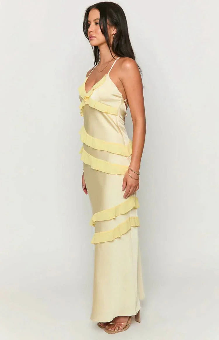 Side profile of a woman wearing a pale yellow Madeline ruffle maxi dress with spaghetti straps and horizontal tiered ruffles.