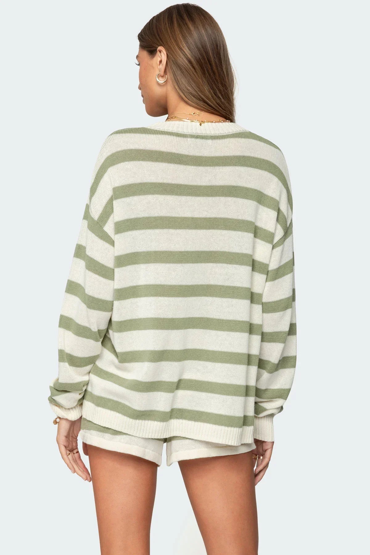 Back view of a woman in a light green and cream striped long-sleeve sweater and matching lounge shorts, showing the full design.