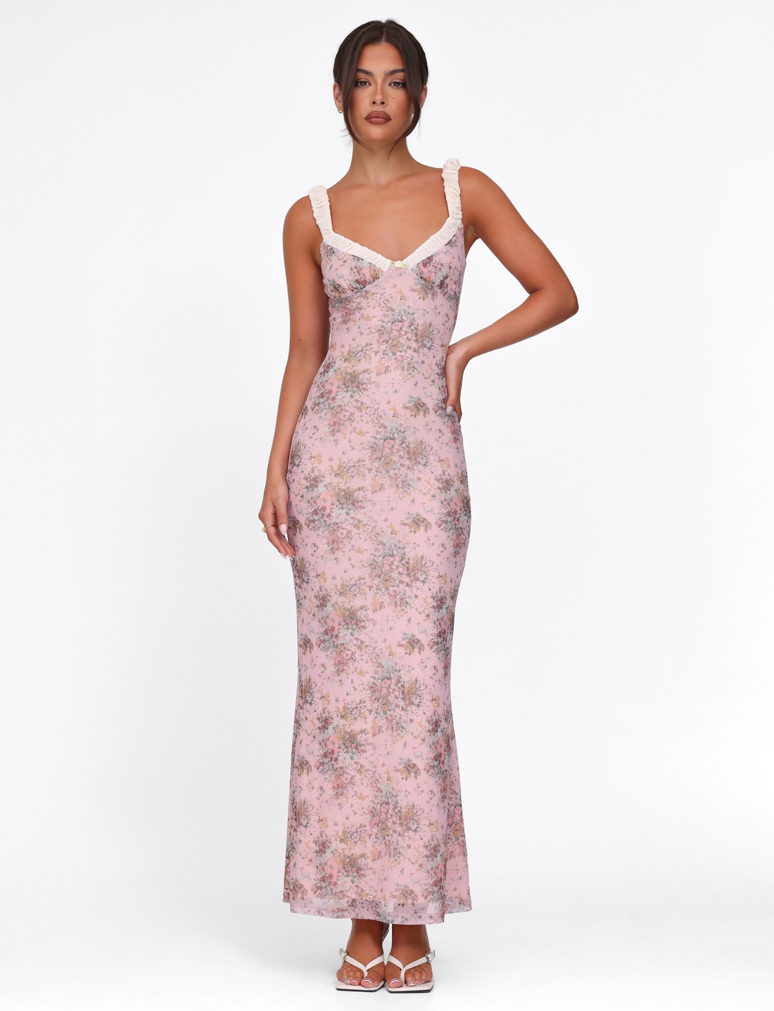 Pink floral maxi dress with white ruffled straps and v-neckline, form-fitting silhouette, perfect for a wedding or event.