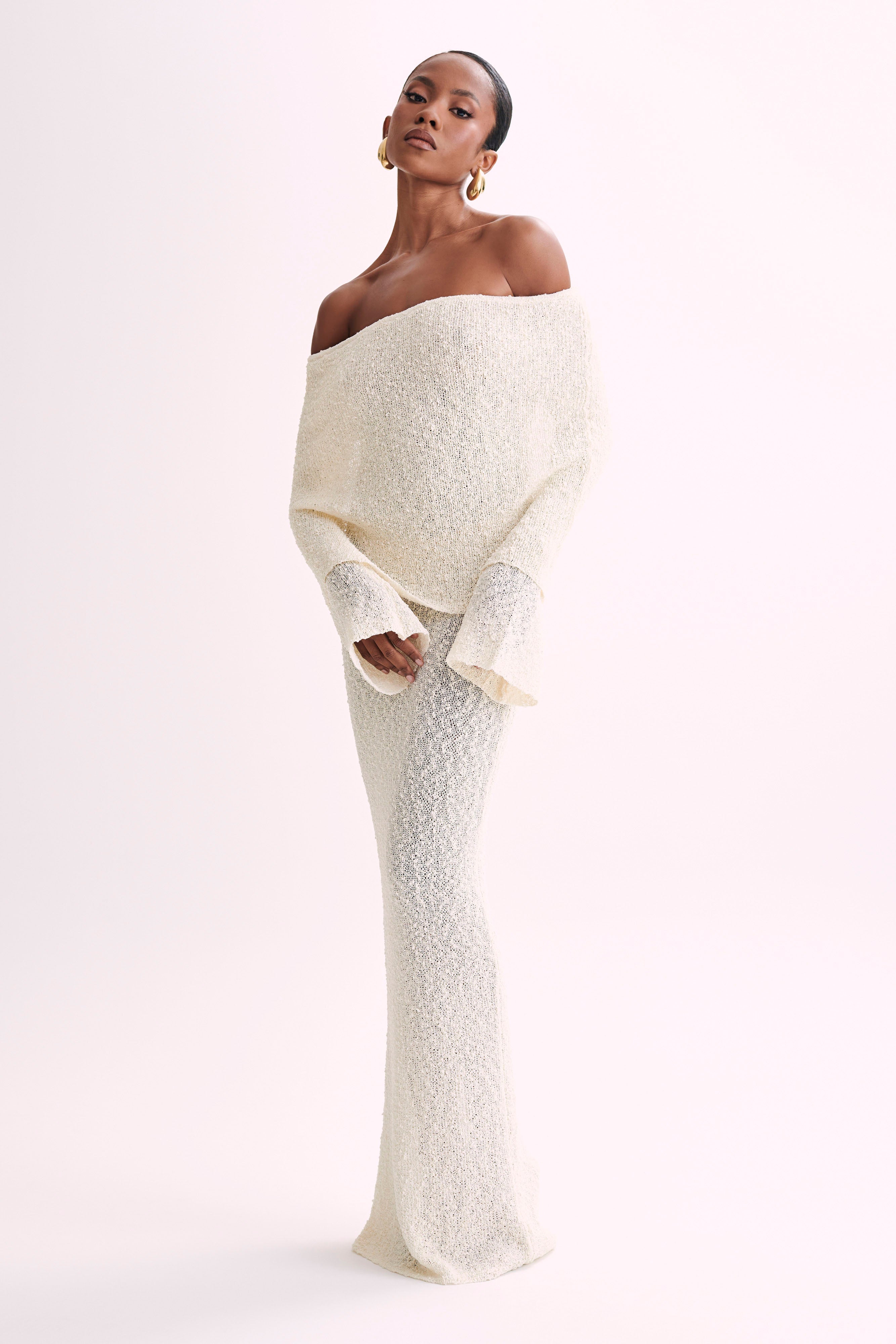 Cream boucle maxi dress featuring an off-the-shoulder design with long sleeves, highlighting the textured fabric.