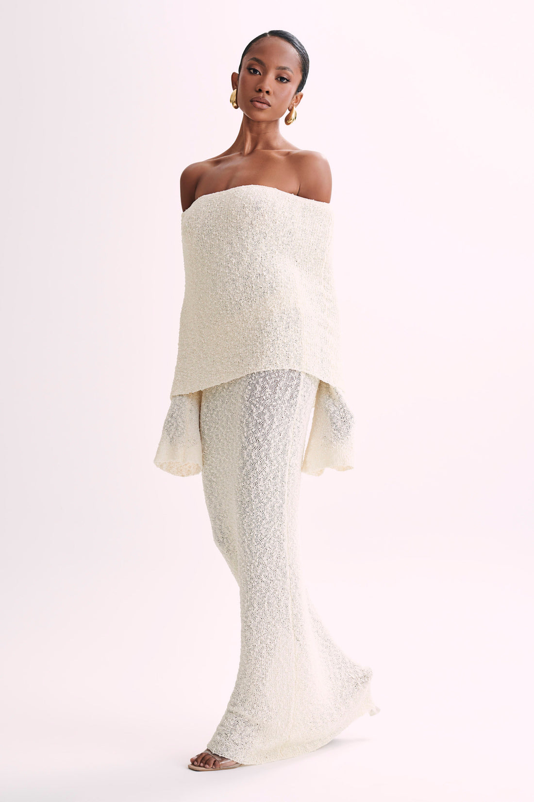 Full-length view of a cream boucle maxi dress with an off-the-shoulder neckline, showcasing the elegant fit.