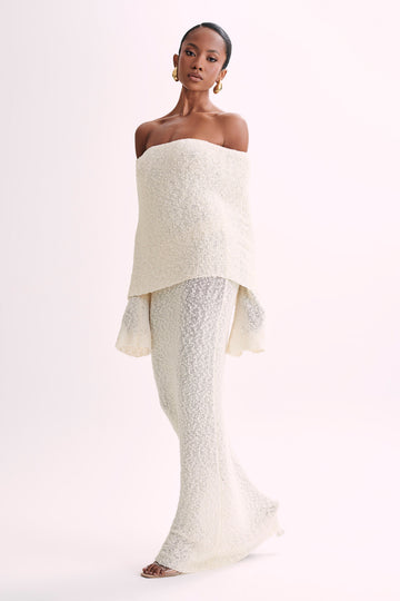 Full-length view of a cream boucle maxi dress with an off-the-shoulder neckline, showcasing the elegant fit.