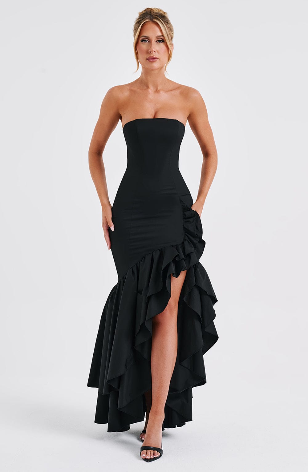 Marlowe Ruffle Maxi Dress in black with a white high-low ruffle skirt, strapless design, and ruched detailing, worn by a model posing outdoors.