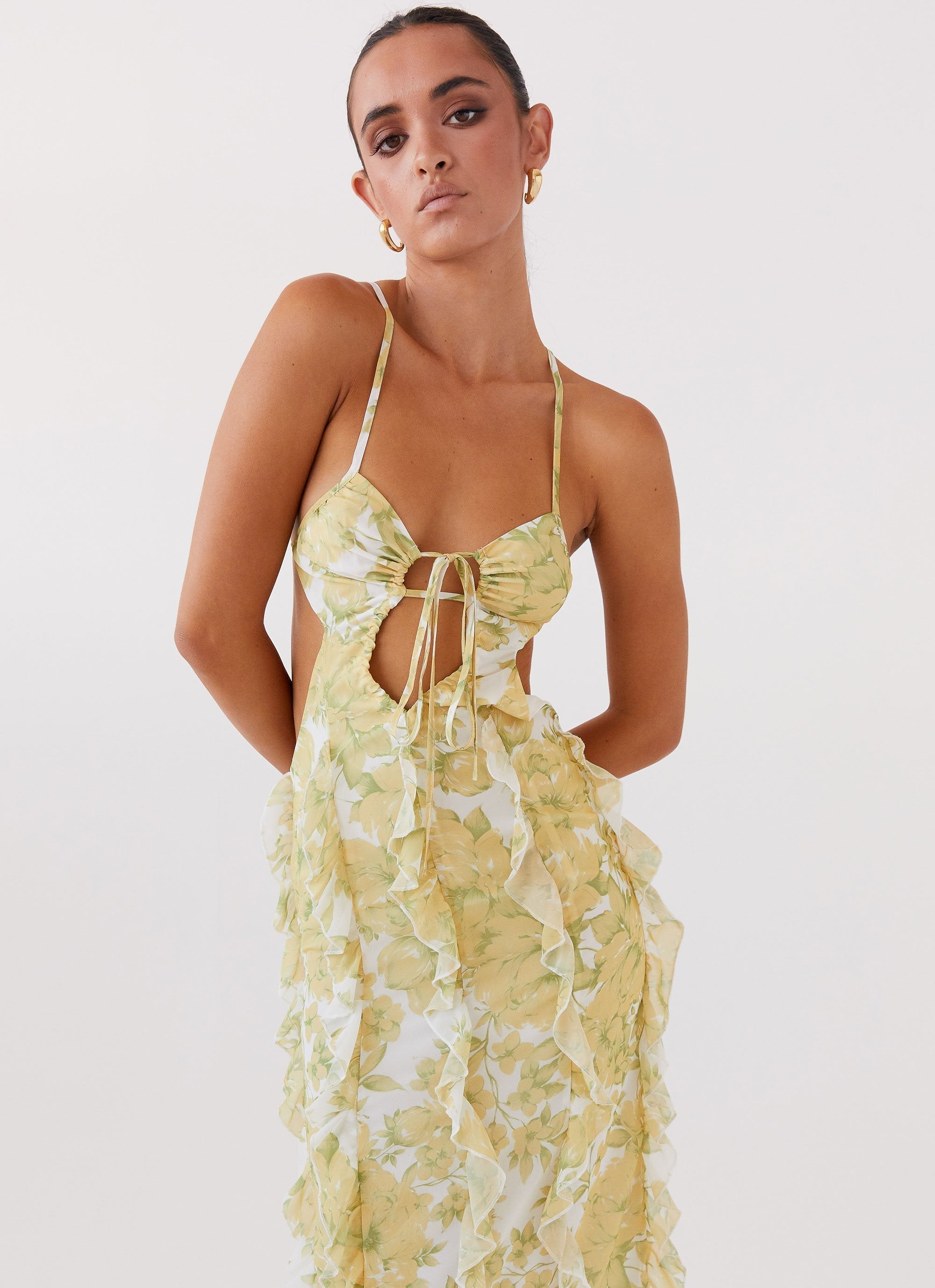 Close-up front view of a woman wearing a white and yellow floral ruffled halter maxi dress for women