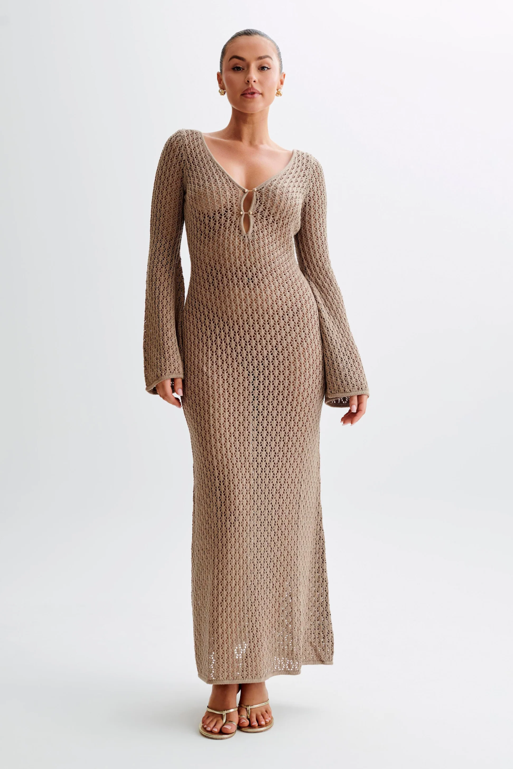 Full length view of a long sleeve deep V-neck brown crochet maxi dress with a front tie detail and bell sleeves, perfect for a beach or resort look.