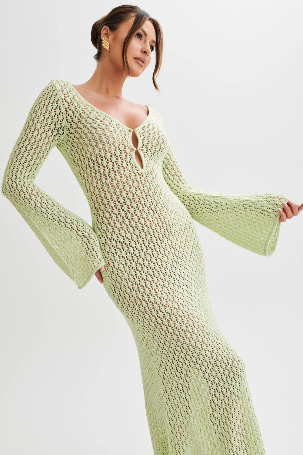 Side profile of a woman in the light green Meadow Crochet Maxi Dress, showcasing the long bell sleeves and elegant drape.
