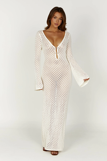 Full-length white crochet maxi dress with long bell sleeves and a deep V-neckline with tie detail.