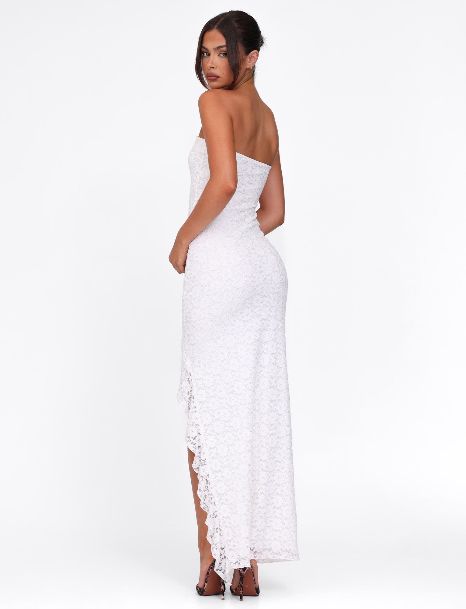 Side profile of a white lace strapless maxi dress, featuring a high-low hem and fitted design.
