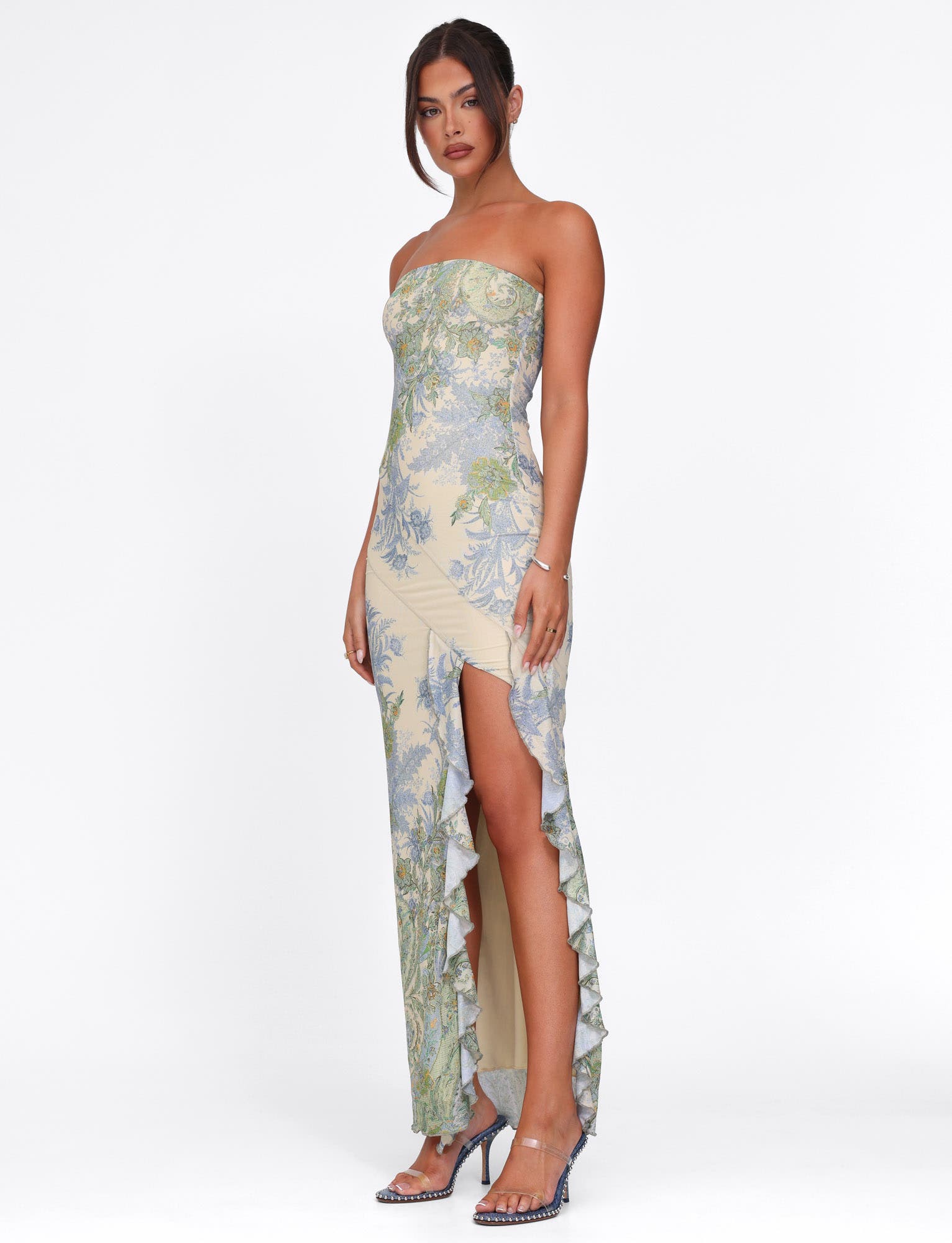Side view of cream Megan Ruffle Maxi Dress with blue and green floral pattern, showing leg through slit.