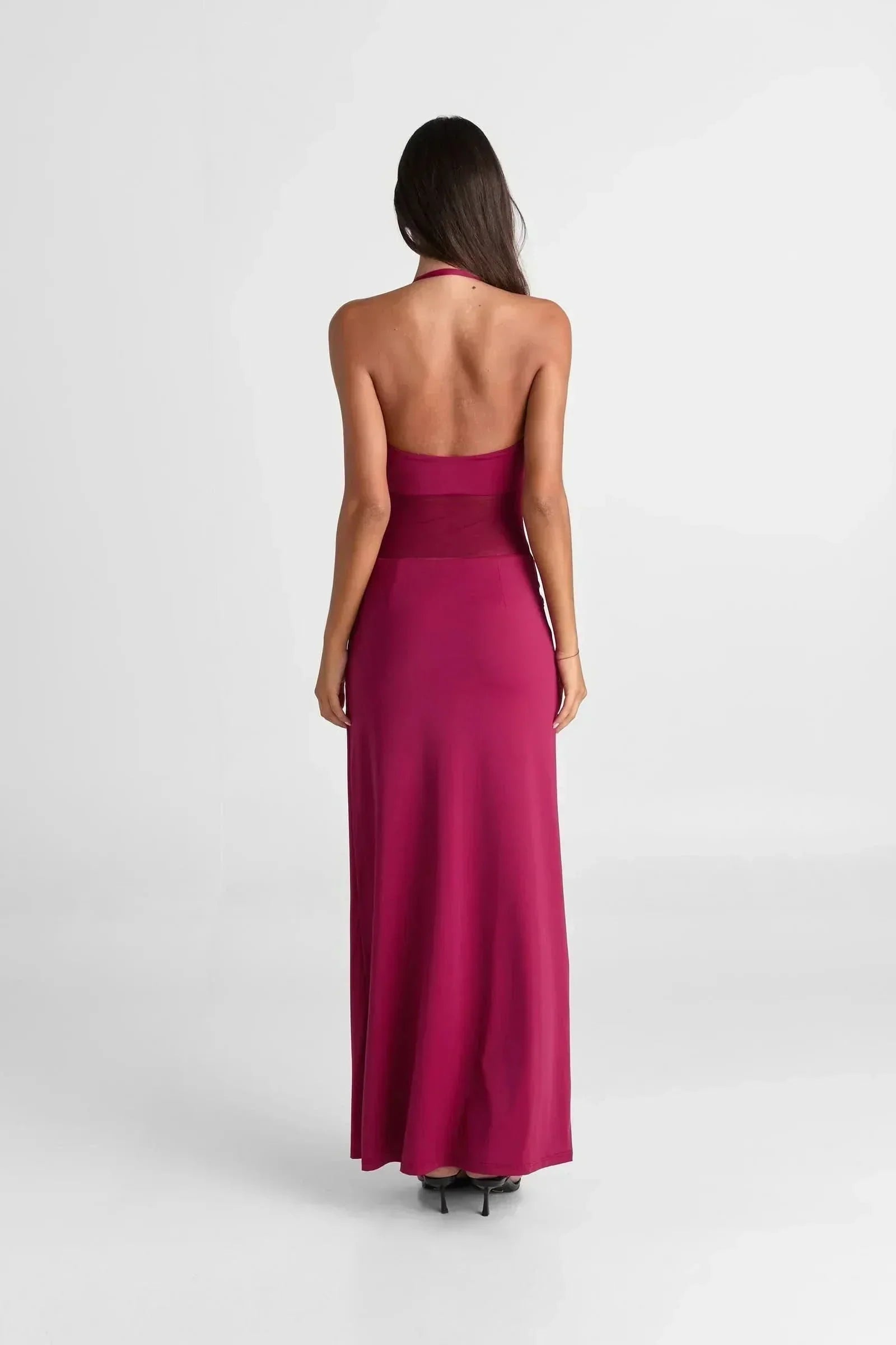 Back view of the Melanie Mesh Maxi Dress in fuchsia, highlighting the open back and long, flowing skirt.