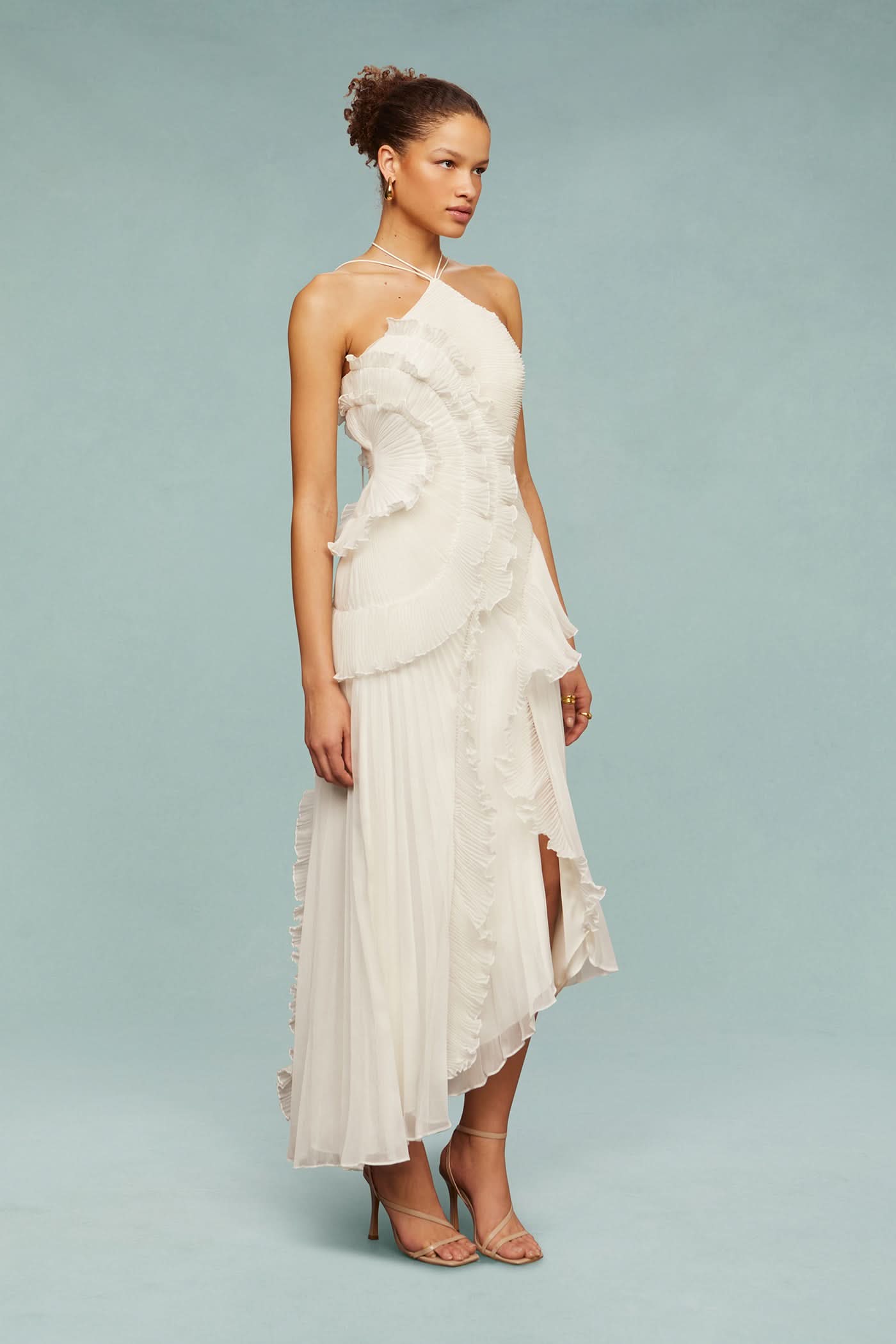 Side profile of a model wearing the white Millie Ruffle Midi Dress, showing the pleated and ruffled details.