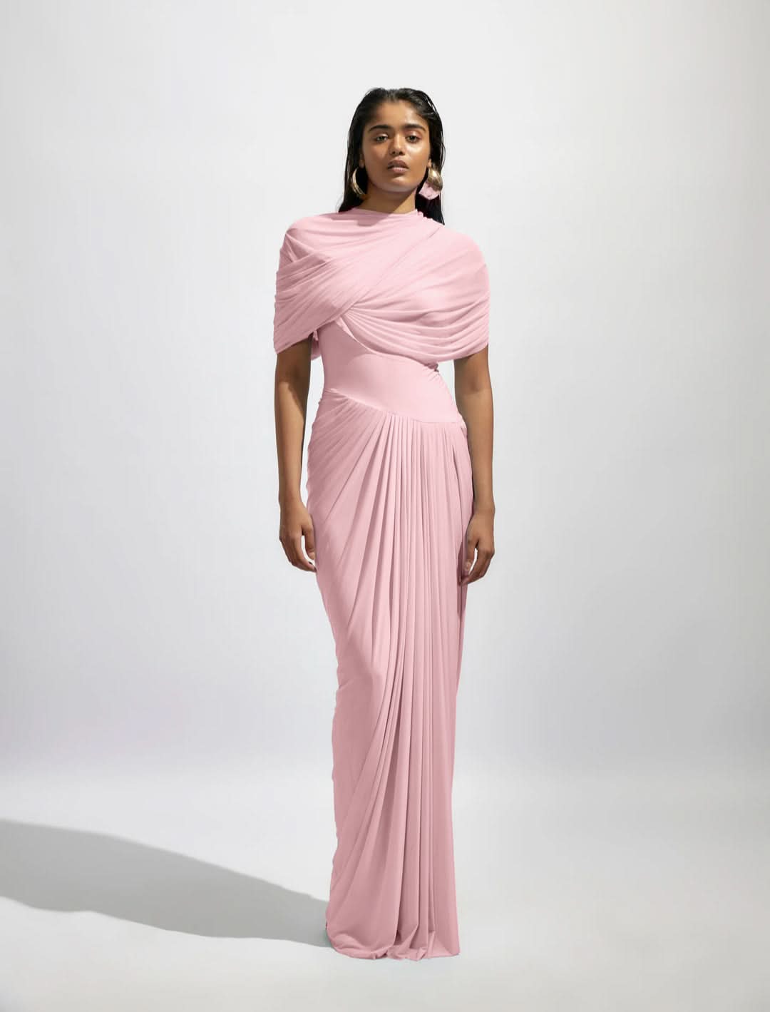 Full-length front view of a pink Mira Draped Maxi Dress, with a draped bodice and pleated floor-length skirt.