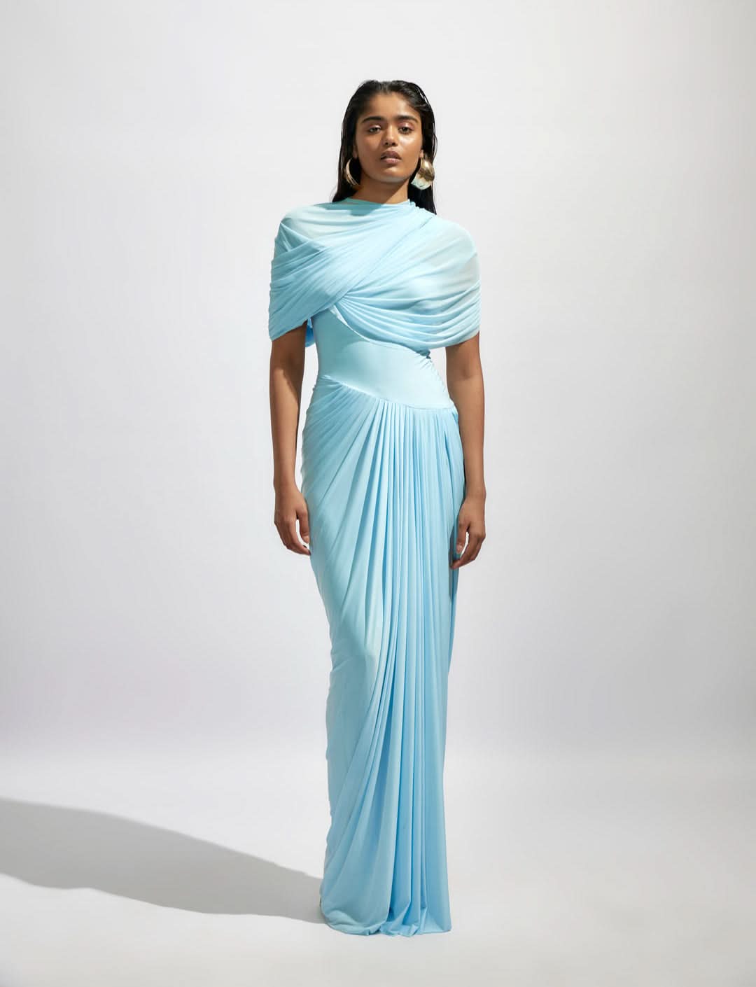 Full-length light blue Mira Draped Maxi Dress with intricate shoulder draping and pleated skirt details, perfect for a wedding.