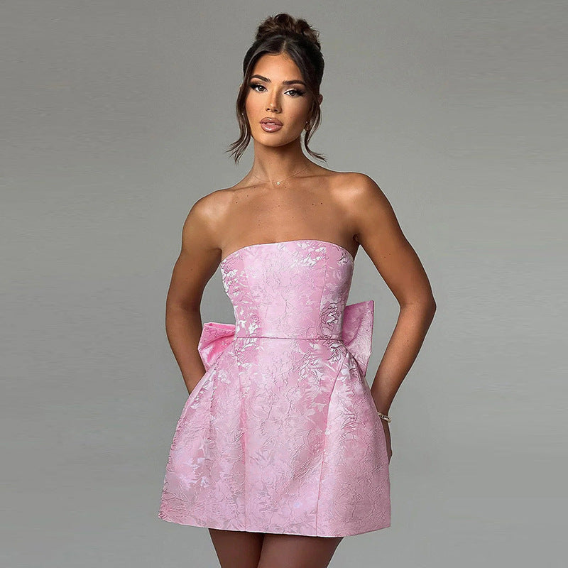 White strapless mini dress with subtle floral jacquard pattern and large side bow detail, perfect for a wedding dress.