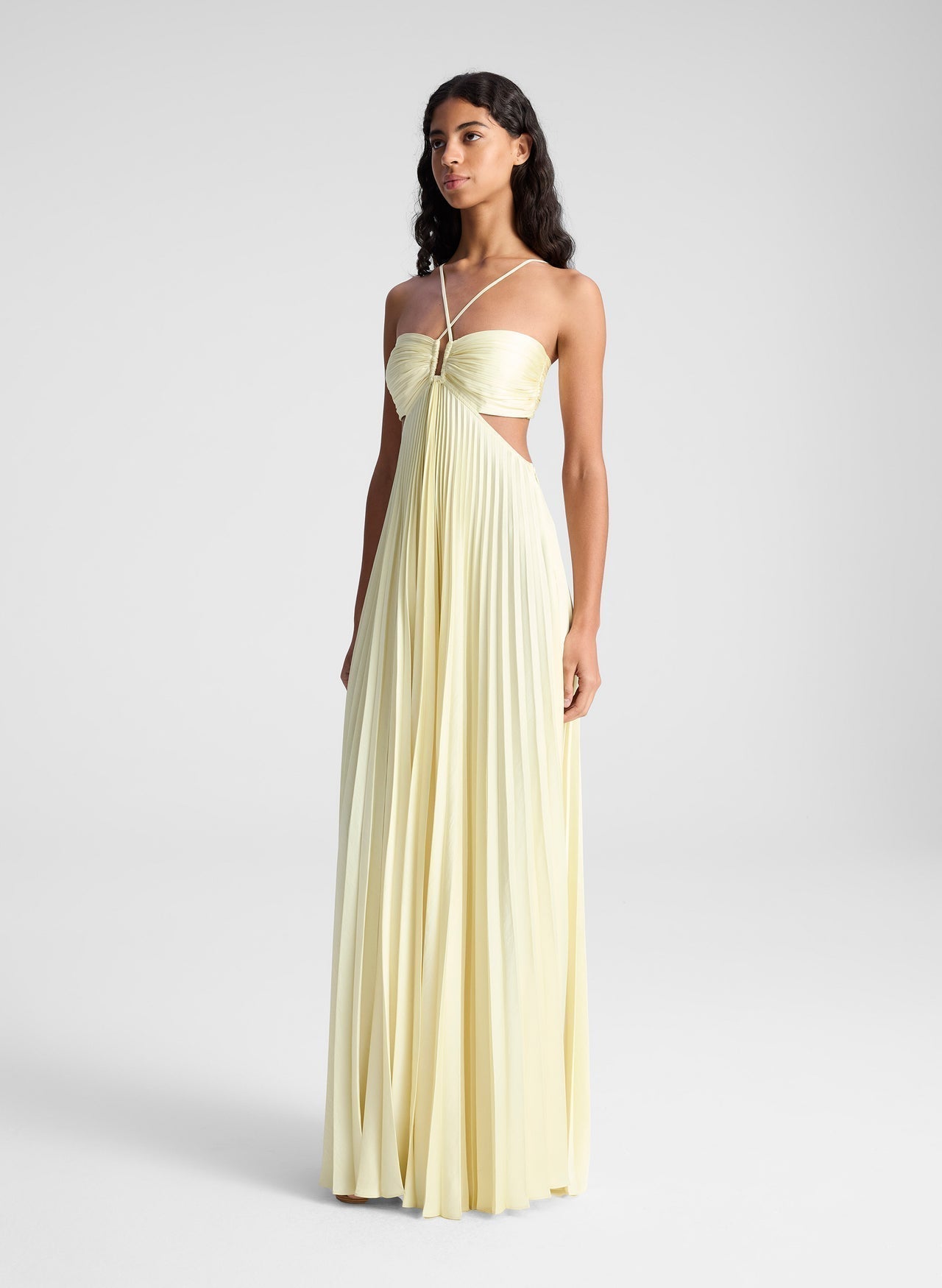 Light yellow pleated maxi dress with side cutouts and halter straps, a flowing women's dress.