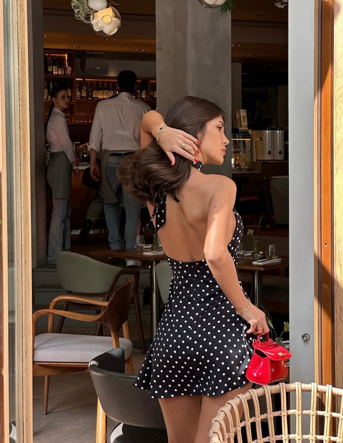 Back view of a black polka dot mini dress, showcasing the halter tie detail and open back design.