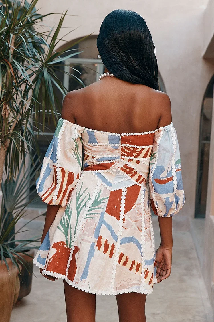 Back view of a woman wearing a multi-colored patchwork mini dress showing the off-shoulder design.