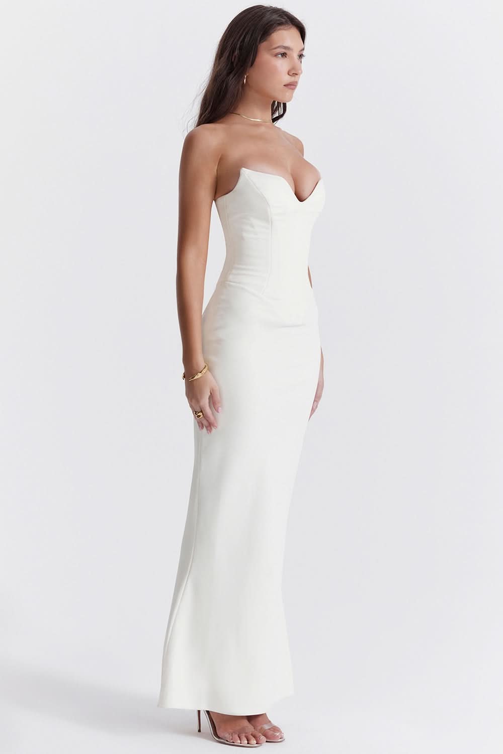 Side profile of a white strapless corset maxi dress, showcasing the fitted bodice and floor-length skirt.