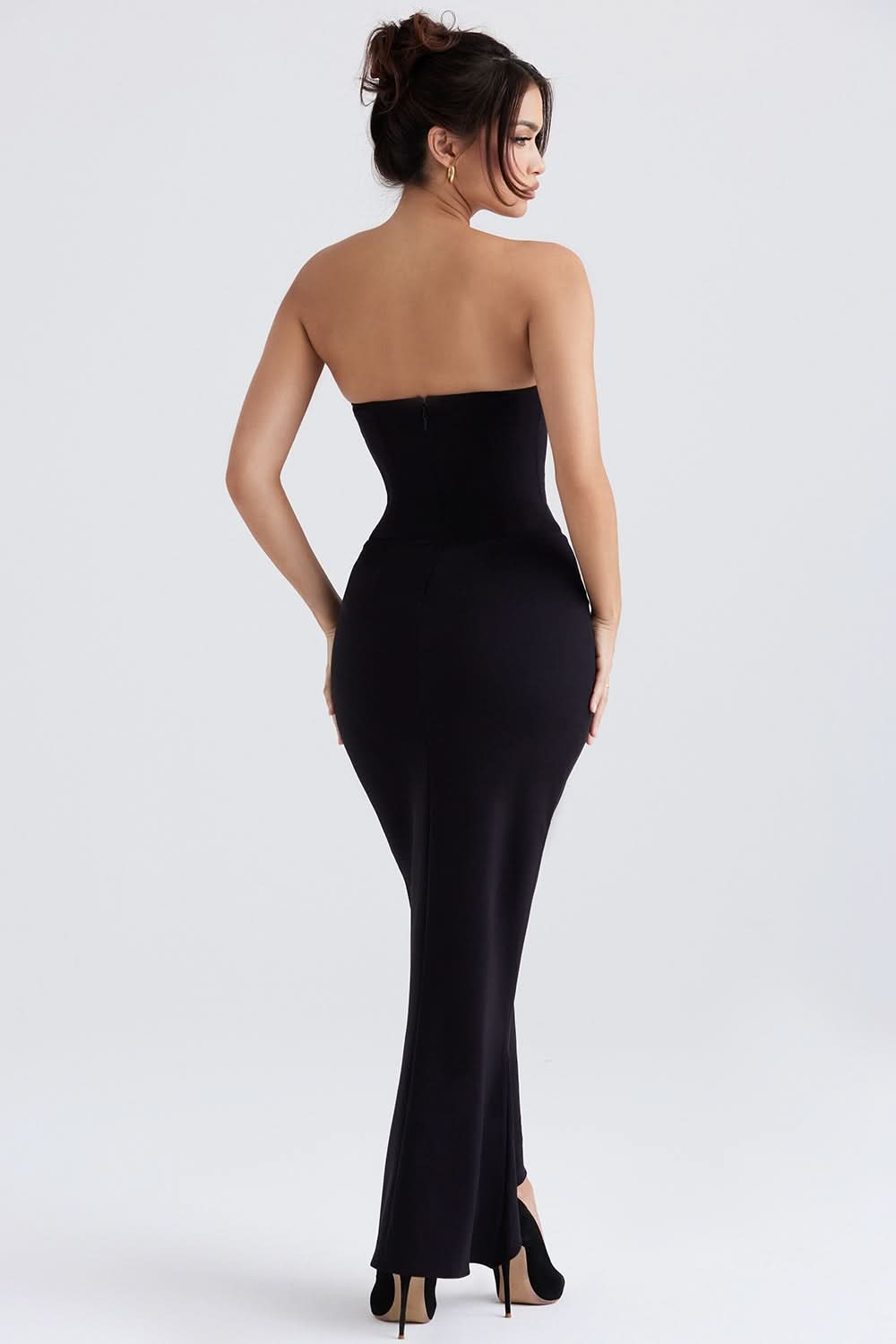 Rear view of a black strapless corset maxi dress, showing the fitted waist and long, flowing skirt.