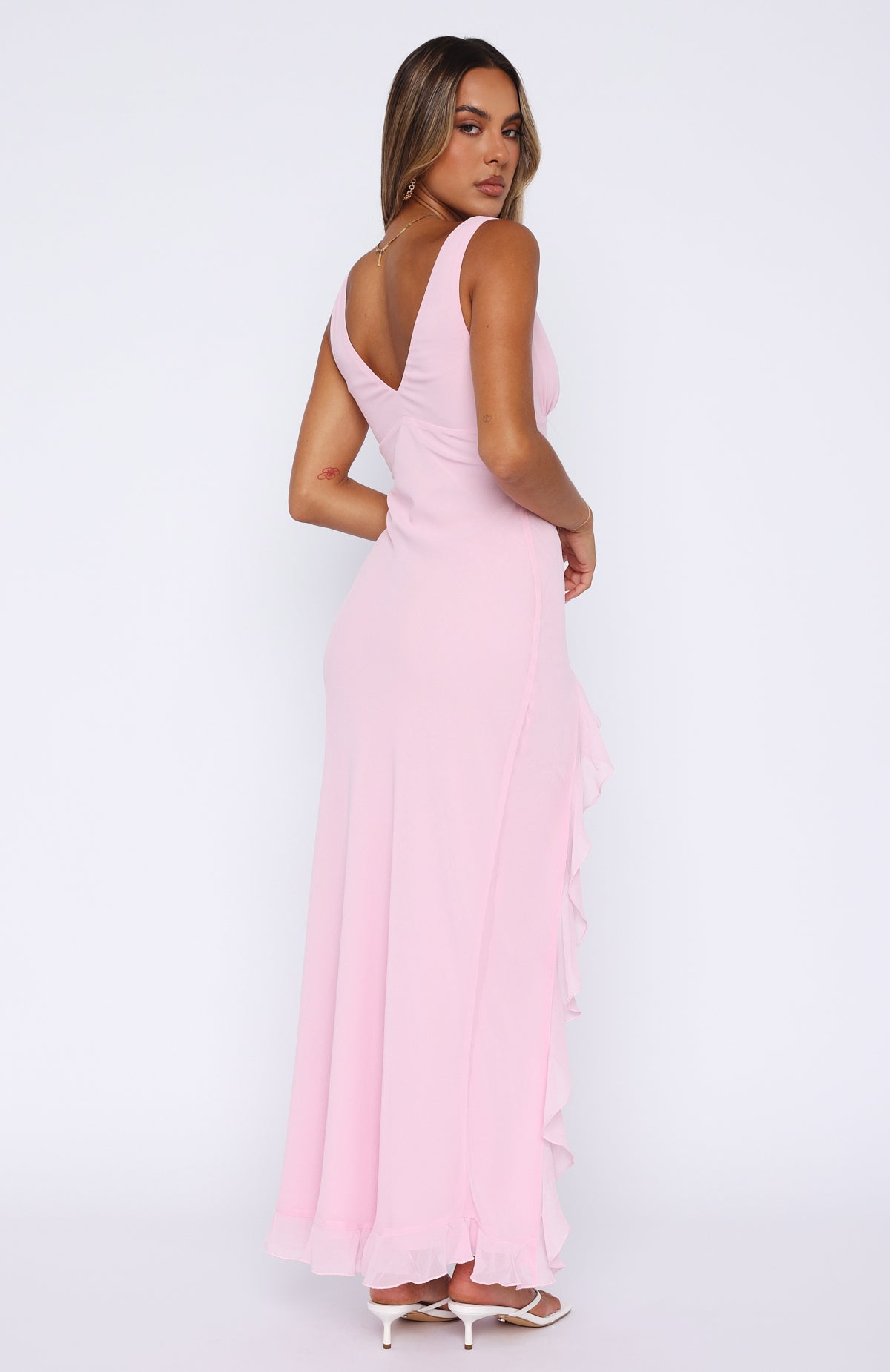 Back view of the pink ruffle maxi dress, showing the deep V-back and the cascading ruffles on the skirt.