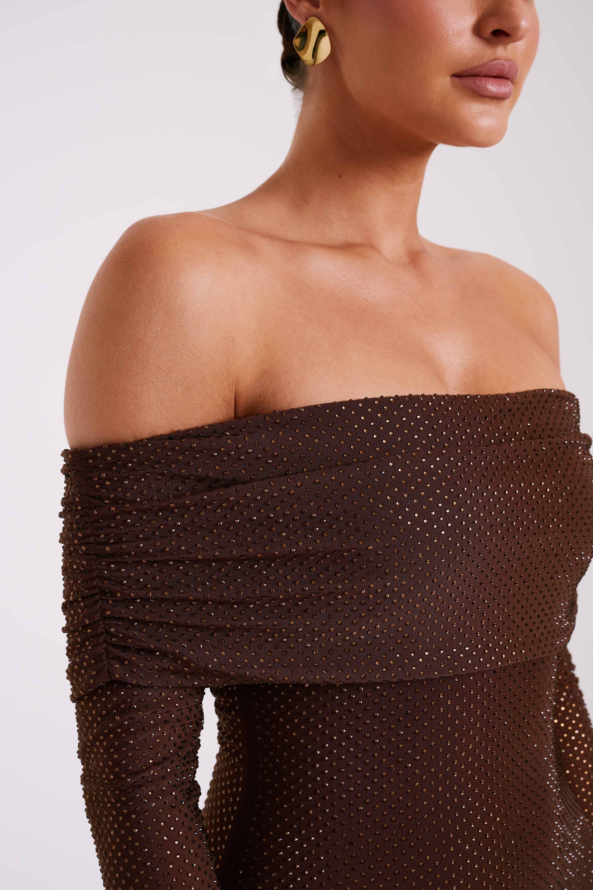 Detail view of the brown glitter mesh fabric and ruched off-the-shoulder design of the dress
