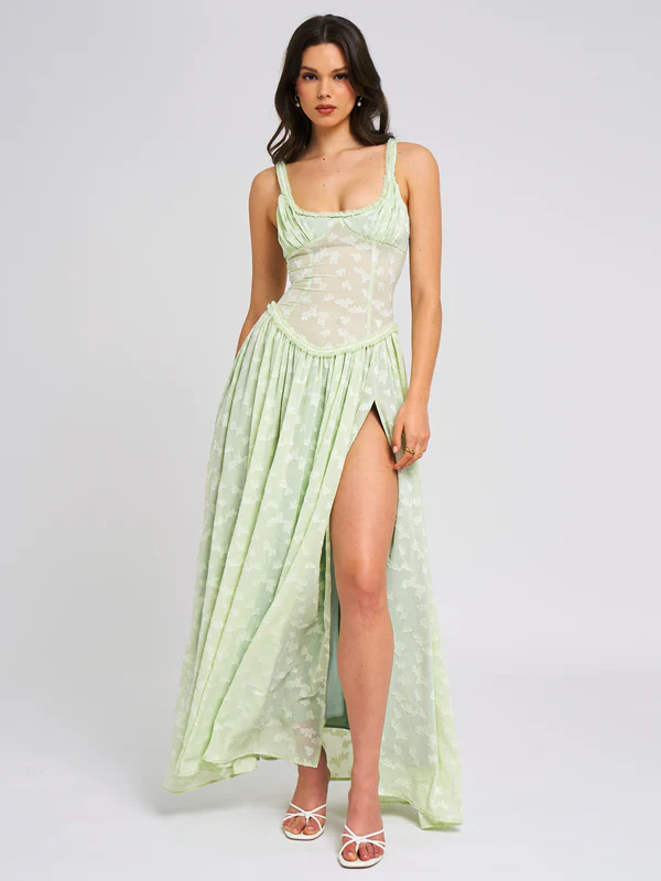 Front view of the light green Nina Corset Maxi Dress, showcasing the sheer corset detail and flowing skirt with a high slit, on a white background.