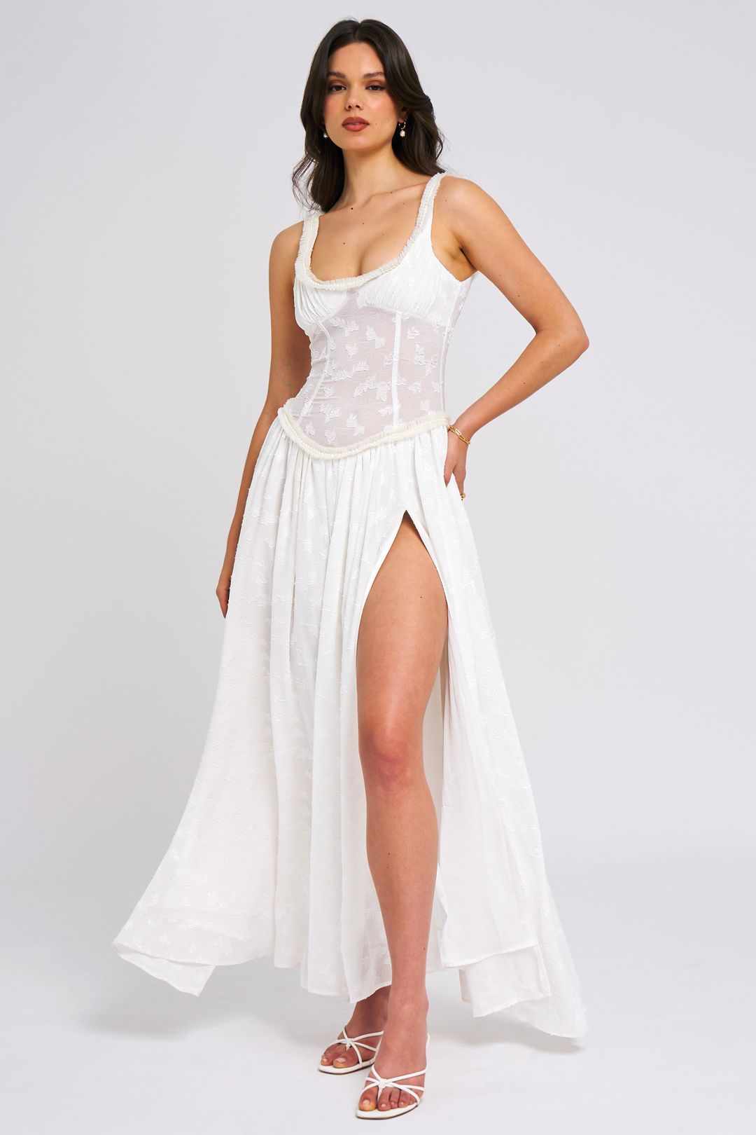 Dynamic pose of the white Nina Corset Maxi Dress, showcasing the movement of the skirt and the elegant design of the corset and slit.