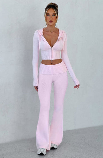 Full body shot of a women's pink casual lounge set, featuring a cropped zip-up hoodie and flared slacks.