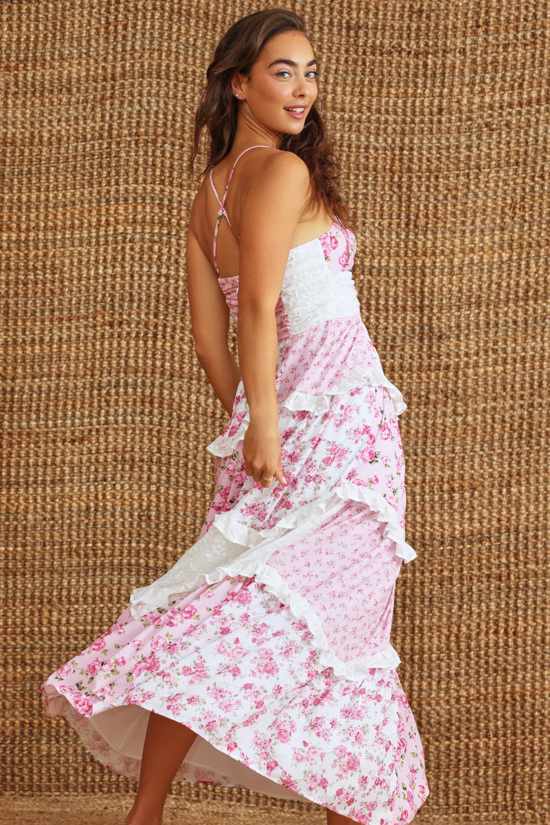 Back view of the pink floral Nola Ruffle Maxi Dress, showing the tiered ruffles, white lace panels, and criss-cross spaghetti straps.