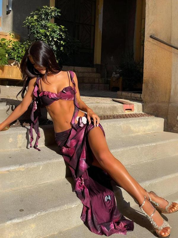 Front view of a woman wearing a purple floral maxi dress with a tie-front crop top and high-slit skirt, posing outdoors.
